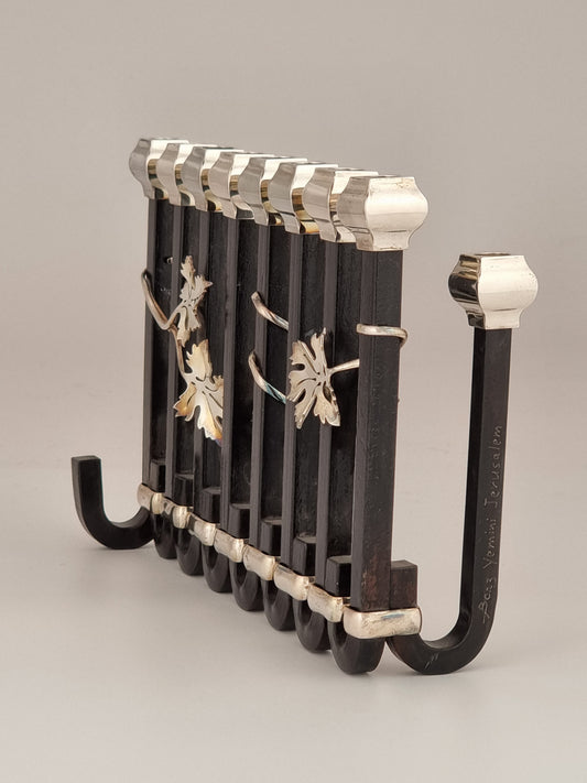 Maccabee Hanukkiah. This extraordinary Hanukkah Menorah was designed in 1996 following a visit to Paris, it was created in sterling silver and blackened steel. It is 8” long and 6½“ high.