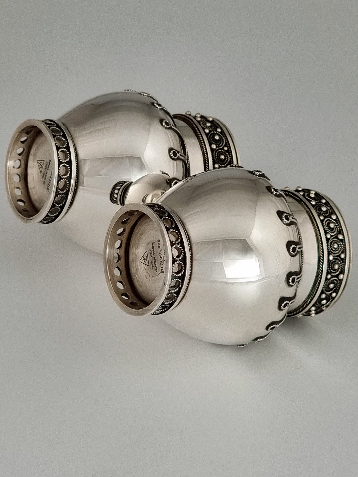 The super-polished belly of these candlesticks stands in contrast to the intricate filigree decorations.