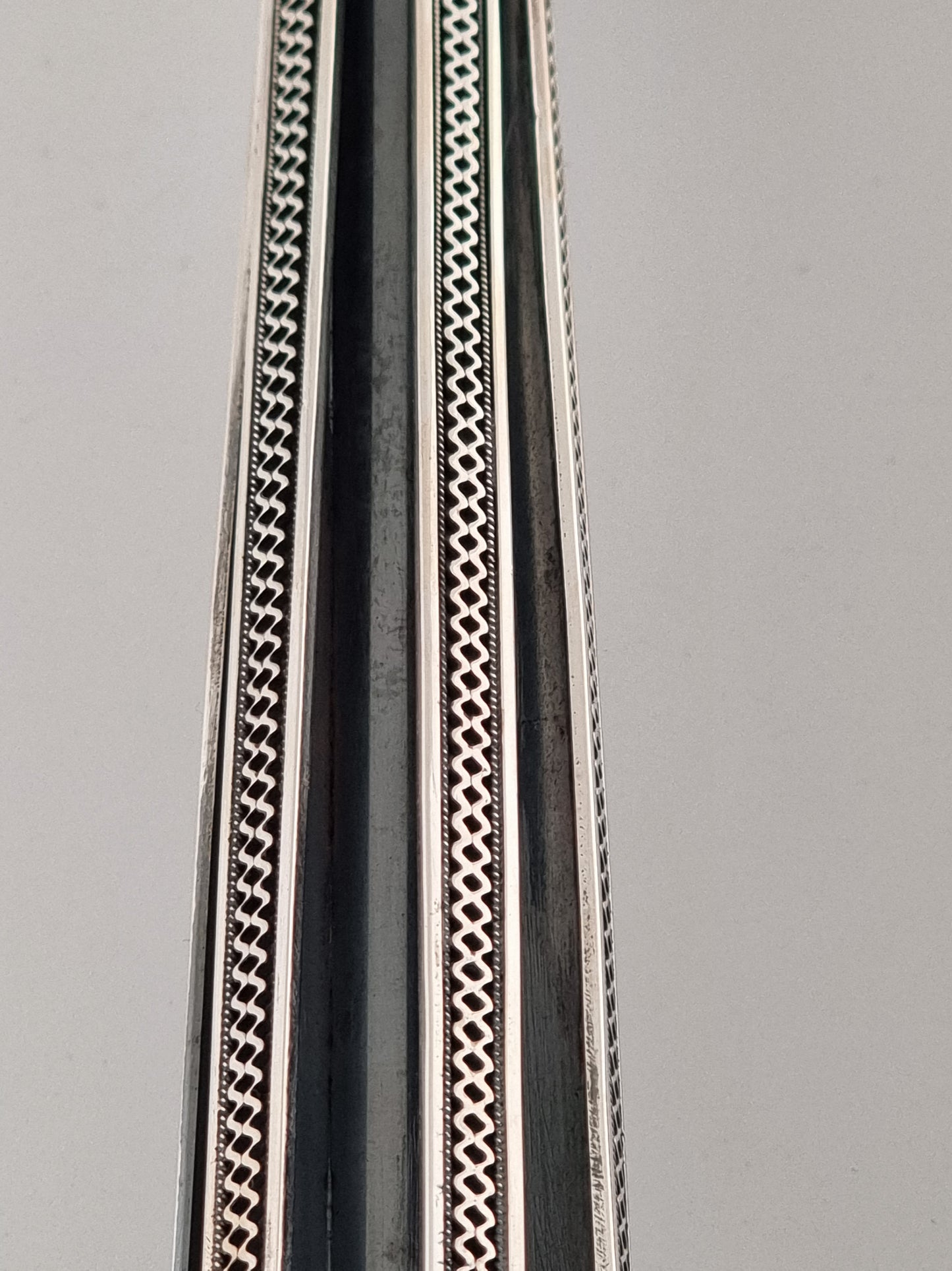 Close-up on the zigzag filigree pattern, divided by deep dark recessed ares.