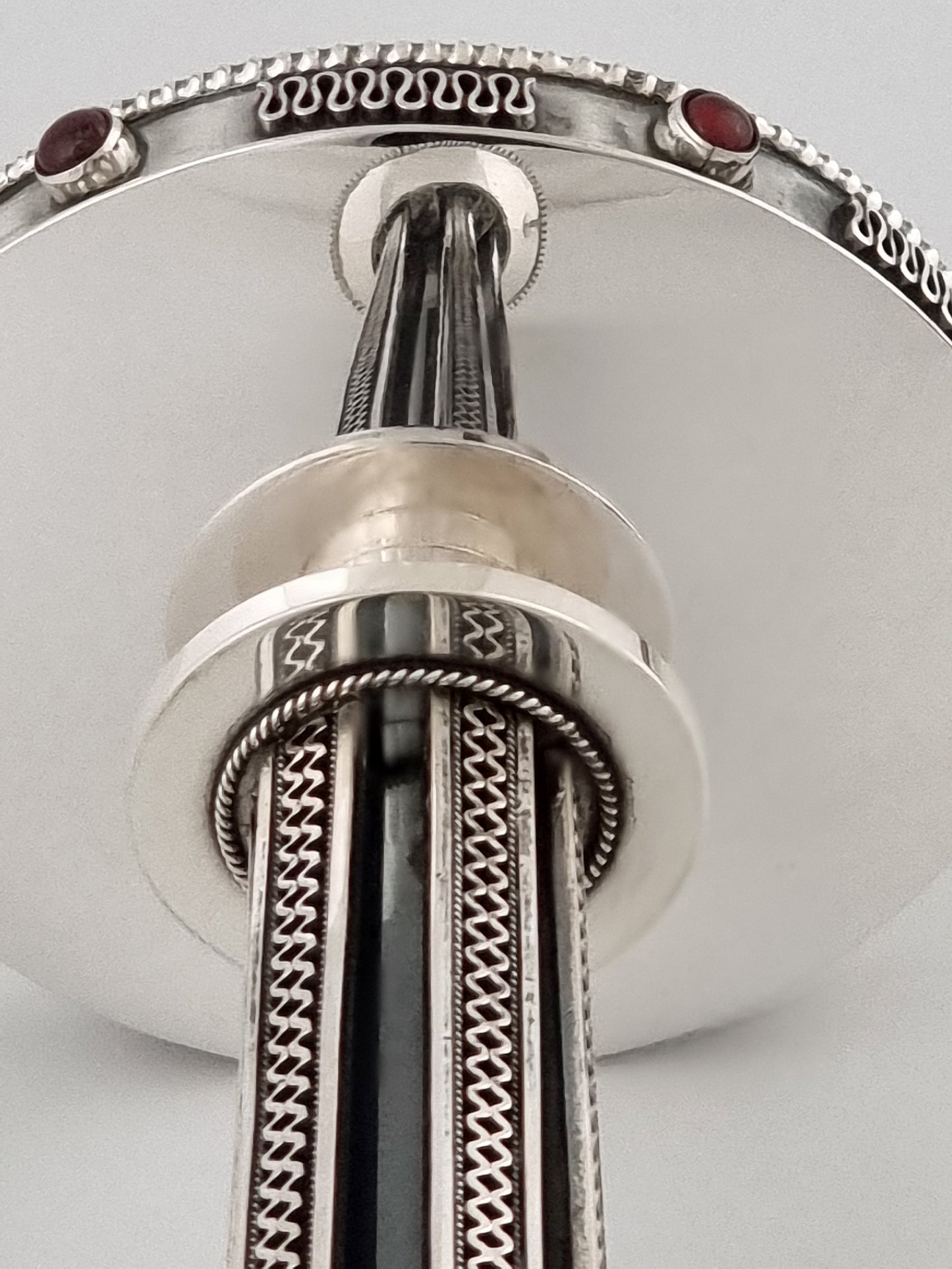 Perfect reflection of a candlestick on its base, which is decorated with garnet stones.