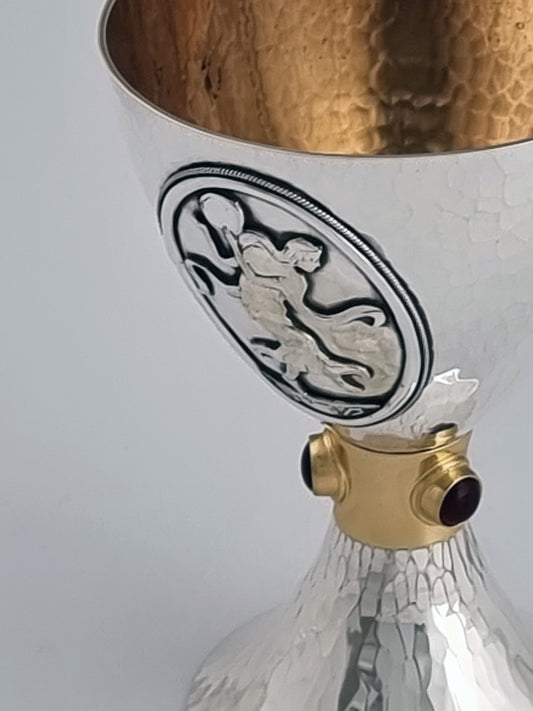 Miriam Kiddush Cup. This cup was designed in 2000. It is made of sterling silver, gold-plated silver on the inside, and adorned with three garnet stones. It measures 5" high.