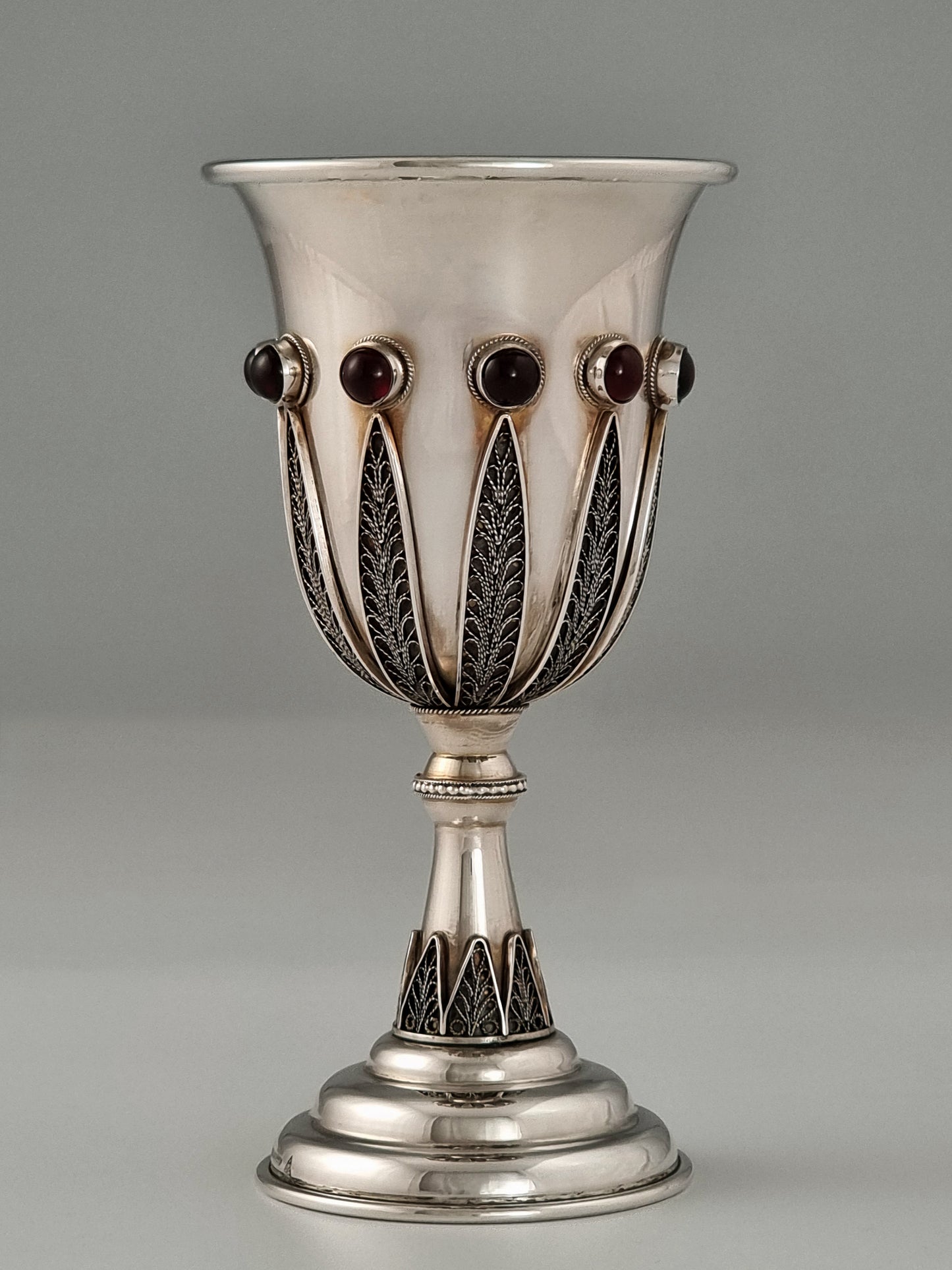 Jacob Kiddush Cup. This cup was designed in the 1960's. It is made of sterling silver, gold-plated silver on the inside, and adorned with ten garnet stones. It measures 5½" high.