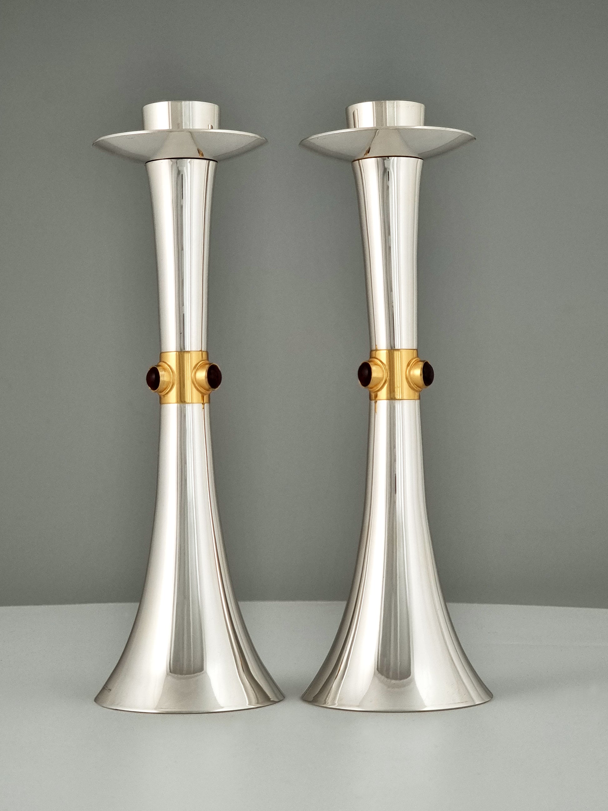 A pair of hyper smooth silver candlesticks with a central gold ribbon
