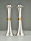 A pair of hyper smooth silver candlesticks with a central gold ribbon