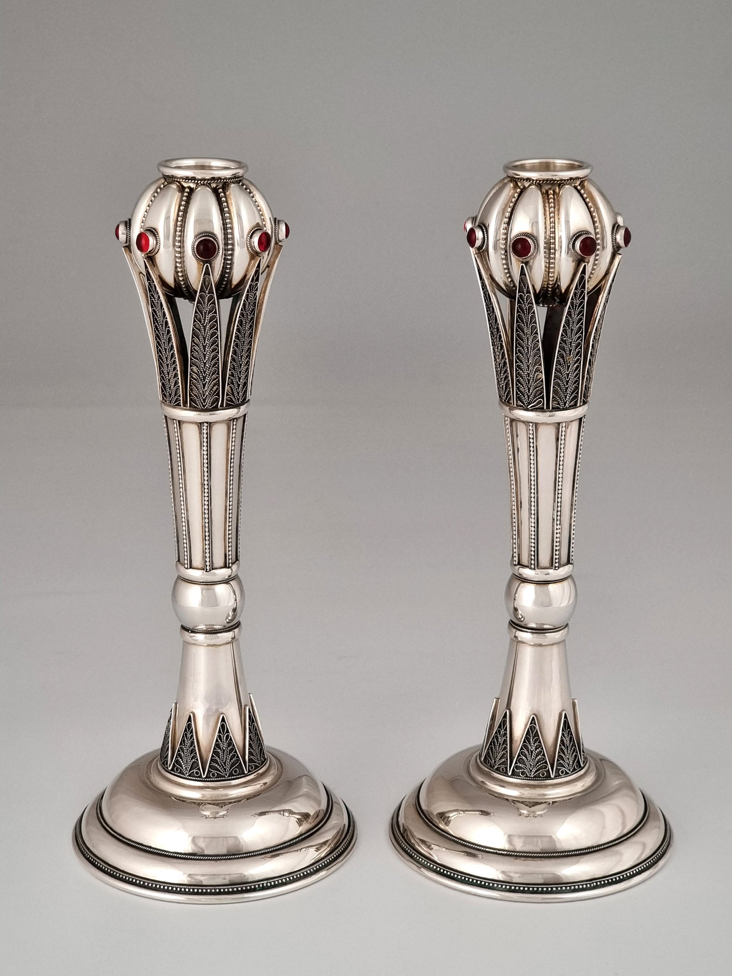 Jacob candlesticks showing multiple silver faces and studded with garnets.