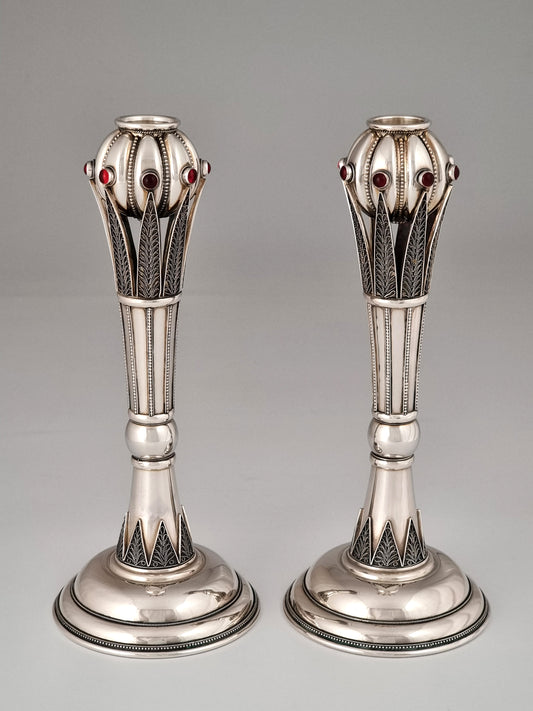 Jacob candlesticks showing multiple silver faces and studded with garnets.
