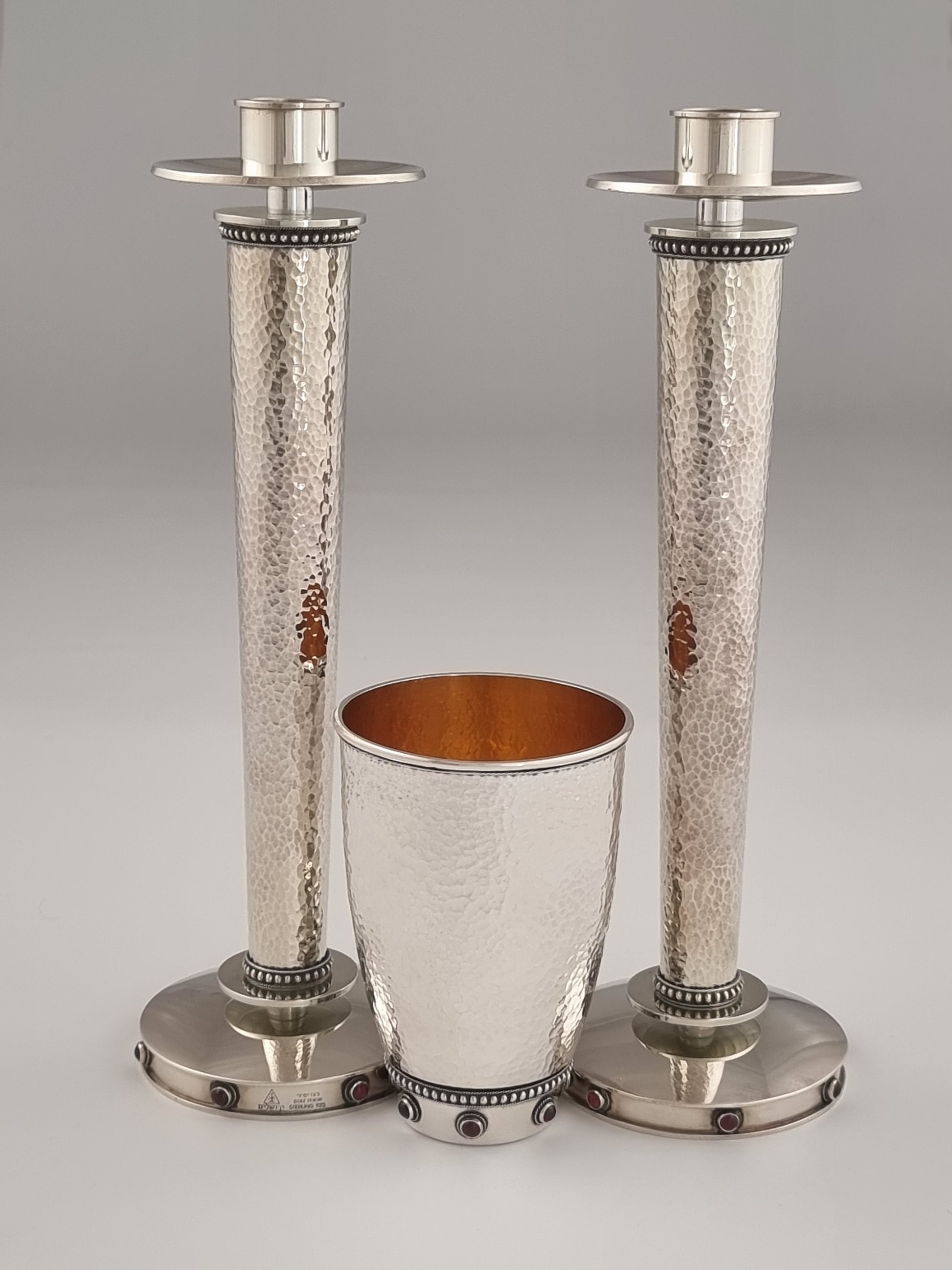 Sarah Kiddush Set. This set was designed in 1999. It is made of sterling silver, gold-plated silver, and adorned with seven garnet stones on each candlestick and ten garnet stones on the cup. The candlesticks are 10” high and the cup is 4½" high.